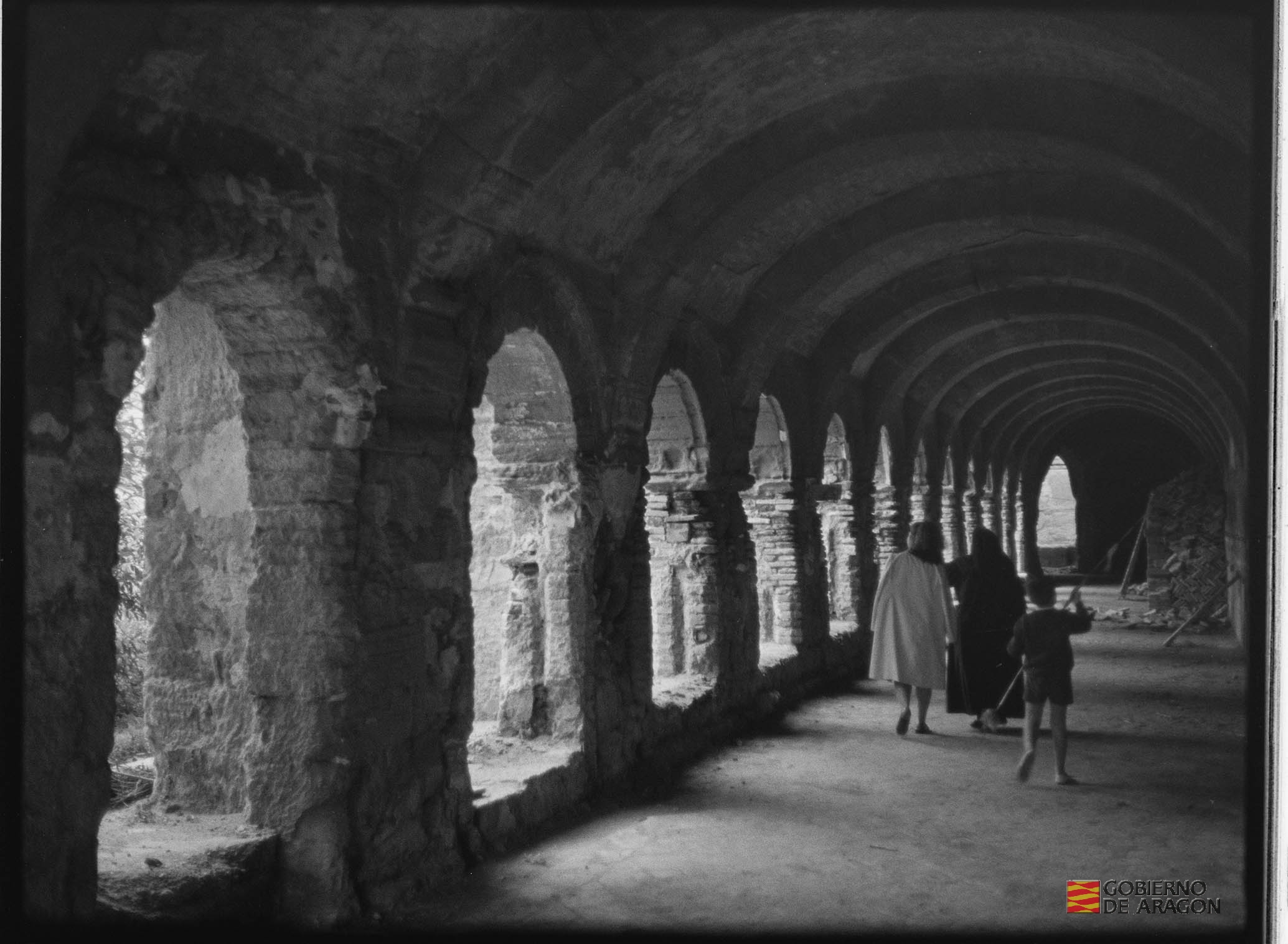 Monasterio de Sigena. Claustro con monja, una señora y un niño de espaldas