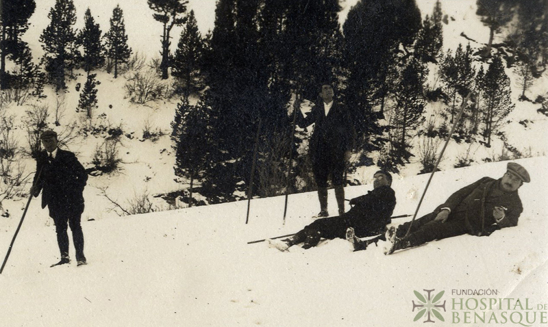 Cuatro hombres con bastones en un paisaje de montaña nevado.