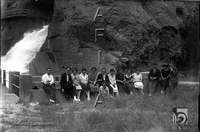 Pantano de la Peña. Grupo de hombres y mujeres sentado delante de la pasarela. Al fondo el aliviadero. Ildefonso San Agustín. Riglos