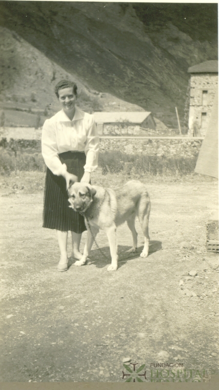Mujer de pie sujetando perro junto al Gran Hotel Benasque