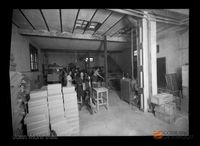 Interior de una fábrica, con los empleados manipulando cajas. Juan Mora Insa