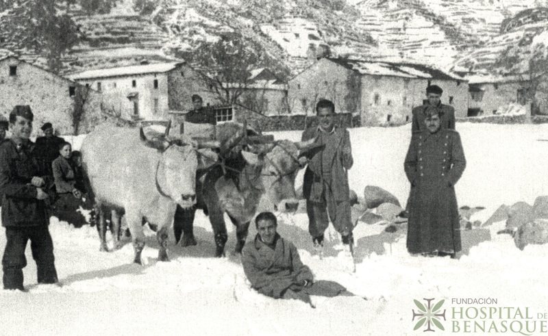 Varios hombres y pareja de bueyes limpiando de nieve un camino en Benasque