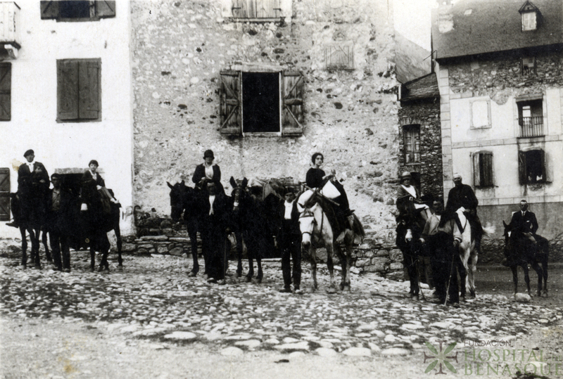 Grupo de personas montadas a caballo en la plaza Mayor de Benasque, junto al puente