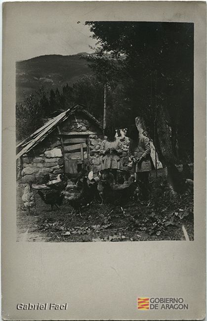 Niñas alimentando a gallinas junto a un gallinero. Gabriel Faci Abad