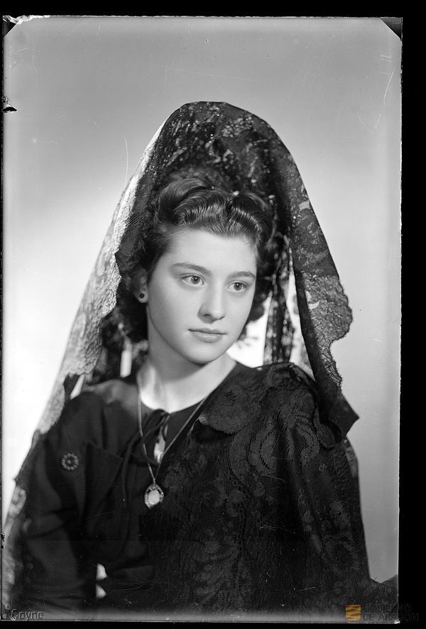 Retrato en plano medio de mujer joven seria, con vestido negro, collar y mantilla
