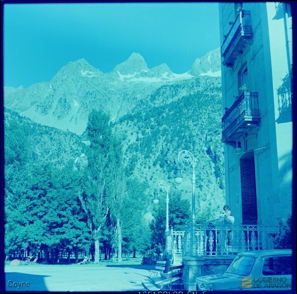 Familia frente a un edificio en el Balneario de Panticosa. Automóvil