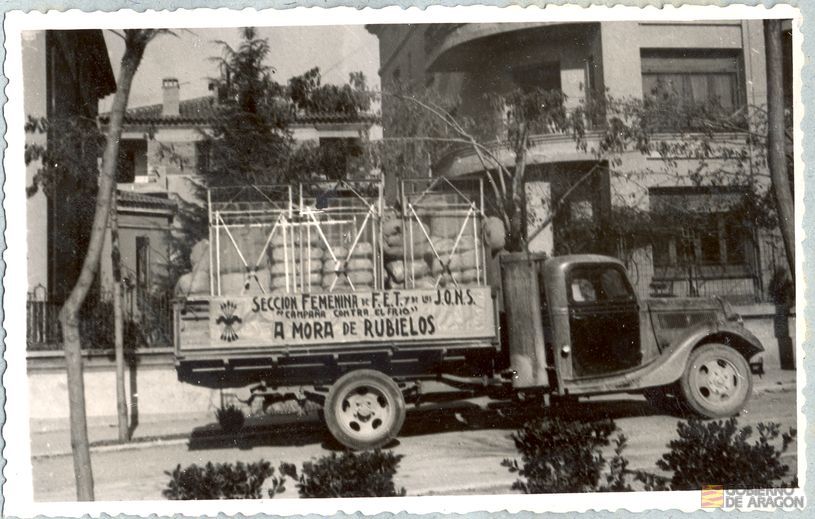 Divulgación y Asistencia. Campaña de invierno. Camión de transporte "campaña contra el frío" estacionado en la puerta del chalet habilitado com Gobierno Civil, en el nº 4 de la calle Fernando Hué del Ensanche, teniendo como lugar de destino Mora de Rubielos. Teruel