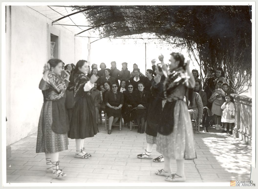 Divulgación y Asistencia. Curso de delegadas locales. Clausura del curso. Bailes de jota aragonesa ante la delegada provincial Rita Navarro Mínguez, autoridades locales y regidoras de la granja escuela San Pascual Bailón de la Sección Femenina, 3 de abril. Alcañiz