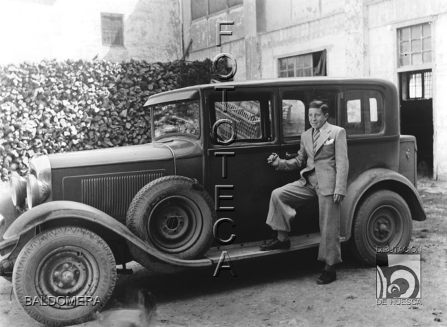 Toñín de Baldomera posando junto a un coche. Antonio López Santolaria. Huesca