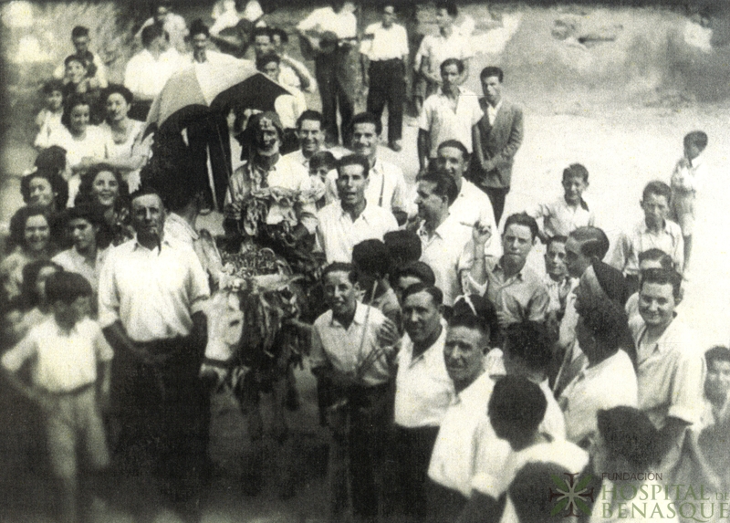 Grupo de personas en torno a un hombre disfrazado montado en un burro