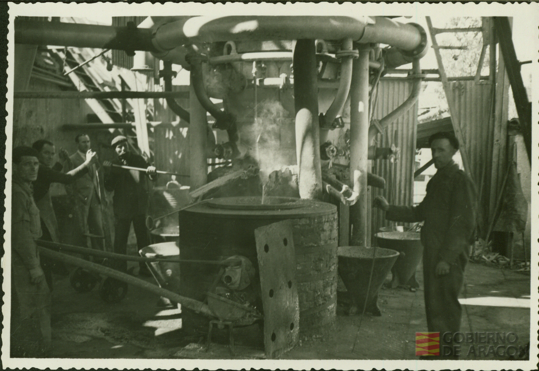Cinco trabajadores de la fábrica Tudor de Zaragoza utilizando la maquinaria propia del sector electrotécnico