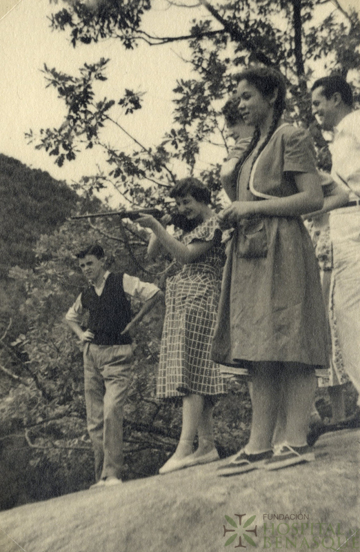 Mujer apuntando con una escopeta, acompañada por dos mujeres y dos hombres