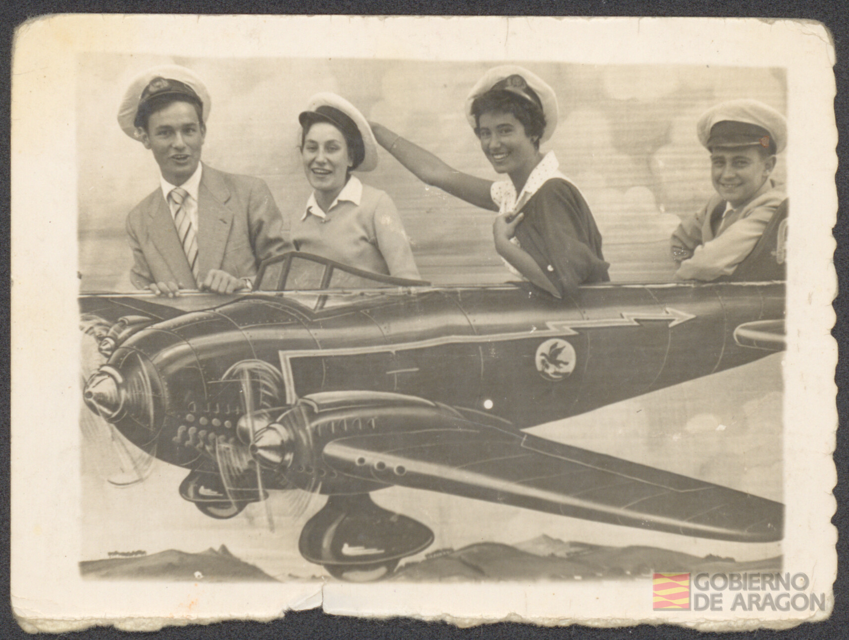 Ángel Conte Cazcarro junto con otros adolescentes apoyados en un panel con la imagen de una avioneta