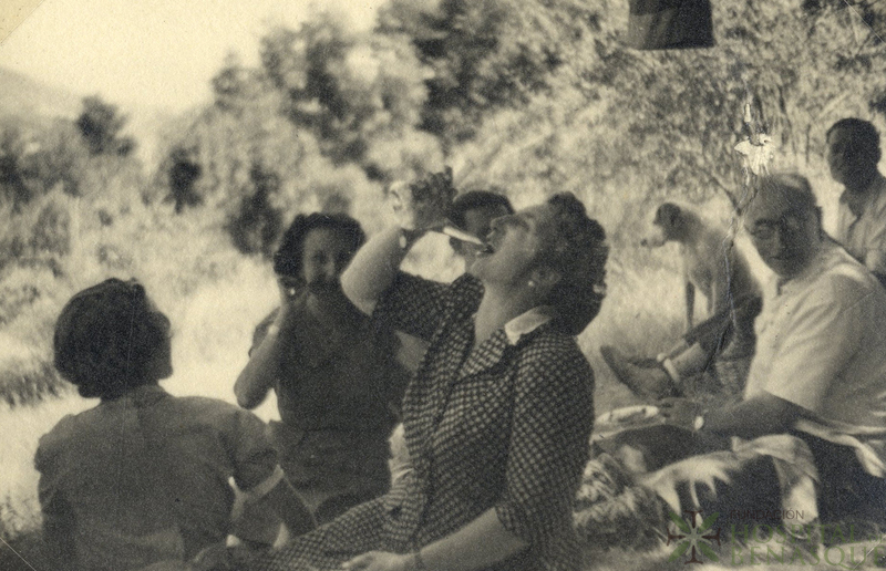 Mujer bebiendo de porrón en una reunión campestre