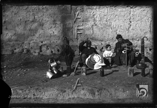Dos hombres y un niño con paraguas, cacerolas y juguetes. Joaquín Galán Bernal. Huesca