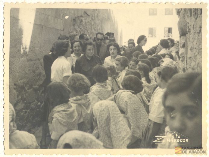 Inauguración albergue de juventudes Rosa Bríos. Pilar Primo de Rivera es recibida a la puerta del albergue en la calle Santa María por niñas uniformadas y sus monitoras. Foto Zaragoza. Albarracín
